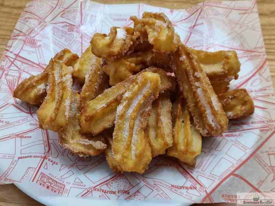 Petits churros sur papier rouge et blanc paraffiné.