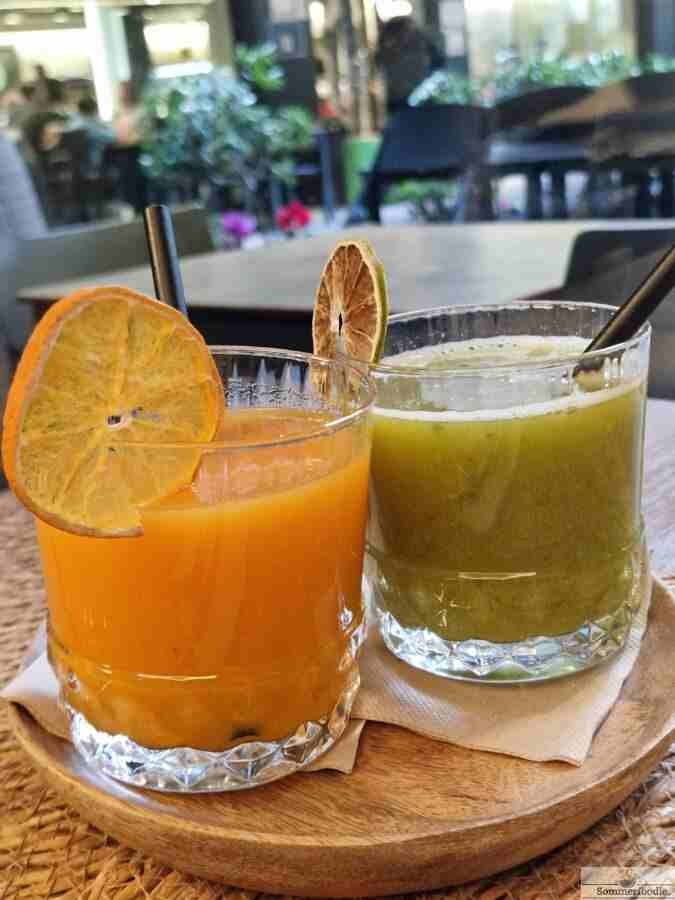 2 verres de jus frais. Un vert et un orange avec tranches d'agrumes séchées